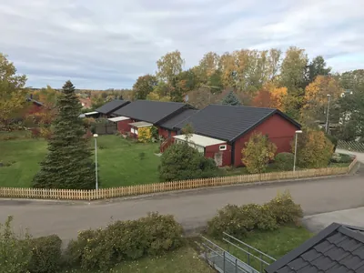 Efter: röd parhuslänga med nybehandlat mörkgrått tak bland höstlöv hos BRF Bergshöjden