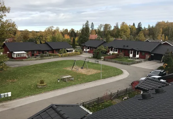 Parhus med röda träfasader och färdigbehandlade mörka tak hos BRF Bergshöjden i Gullspång, med lekplats