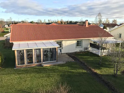 Efter: vit villa med inglasad veranda och rött färdigbehandlat tak hos BRF Broby 2
