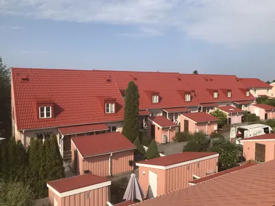 Efter: den rosa radhuslängan med färdigbehandlat rött tak och kupor hos BRF. Ekvecklaren
