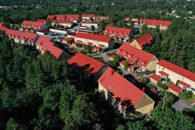 Efter: hus och gårdar hos BRF. Ekvecklaren i Huddinge, nybehandlade röda tak mellan tallar