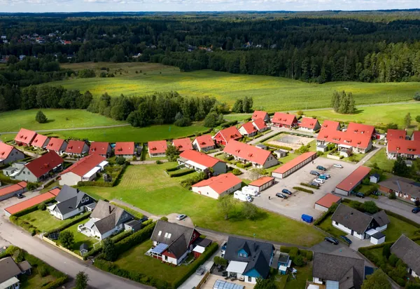 Drönarbild över BRF. Gamleby i Osby med röda, färdigbehandlade tak på radhus bredvid åkermark