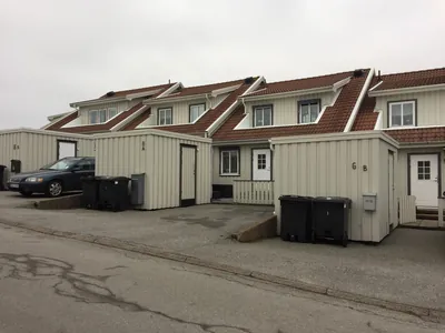 Före: beige radhus och förråd med mörka, nedsmutsade tak hos BRF Gjutaren i Lysekil