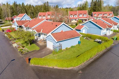 Före: hörn av BRF. Gråsparven med blåmålade hus och slitna betongpannor, drönarbild