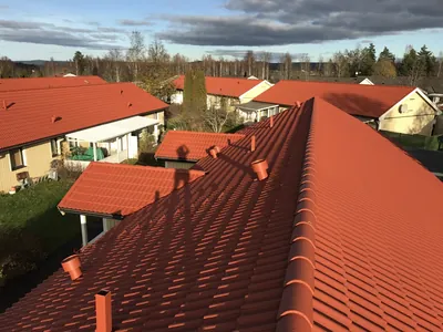Efter: takkam med färdigbehandlade orangeröda pannor, gula hus i bakgrunden, BRF Hea i Sunne