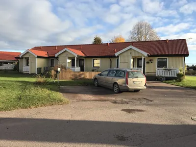 Efter: gul radhuslänga med nybehandlat orangerött tak sedd från vägen hos BRF Hea