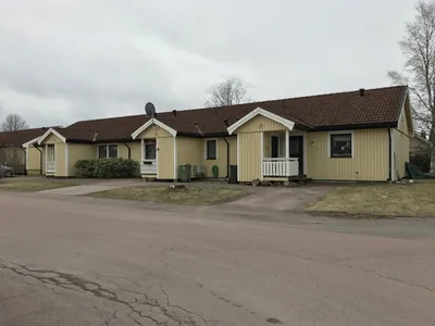 Före: gul radhuslänga med bruna, slitna betongpannor sedd från vägen hos BRF Hea