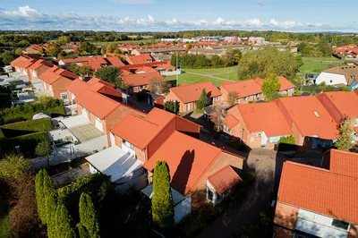 Efter: drönarbild längs radhusen i Ödåkra med färdigbehandlade kopparbruna tak i solljus