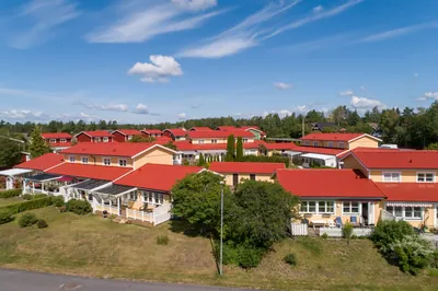 Efter: radhuslänga med gula fasader och färdigbehandlade röda tak hos BRF. Karlstadshus nr 7
