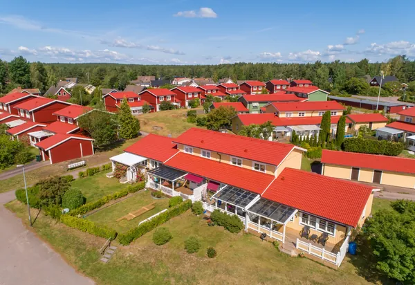 Radhuslänga med gula och röda trähus hos BRF. Karlstadshus nr 7 i Skattkärr med färdigbehandlat rött tak