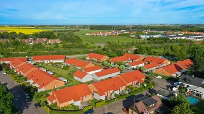 Efter: radhuslängor hos BRF. Kommendanten i Kävlinge med jämna, tegelröda tak mot blå himmel