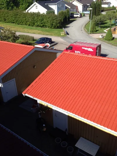Efter: nymålat rött garagetak hos BRF Lindås med företagets bil på gatan nedanför