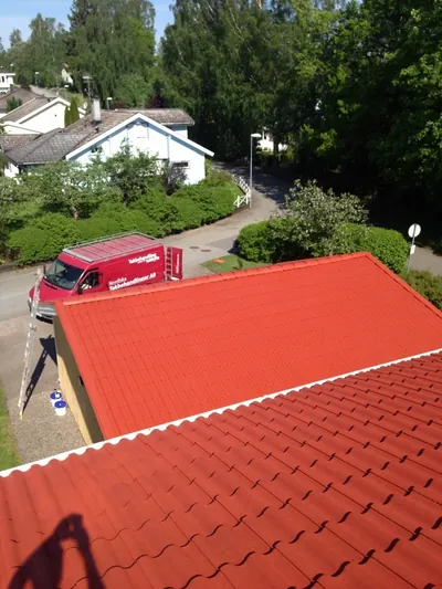 Efter: färdigbehandlat rött tak hos BRF Lindås med firmabilen vid infarten