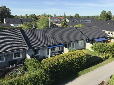 Efter: radhusrad med jämnt mörkgrått tak och blå markiser hos BRF Mobacka i Örebro