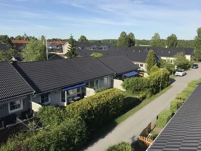 Efter: radhuslänga med färdigmålat mörkt tak och häck, fotad uppifrån hos BRF Mobacka