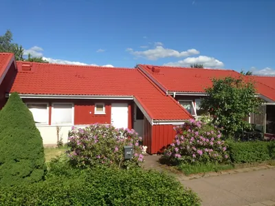 Efter: rött radhus hos BRF Österhöjden med nymålat rött tak och blommande buskar