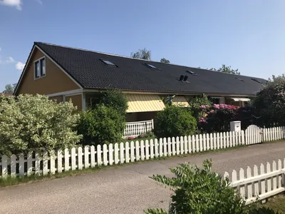 Efter: radhuslänga med färdigbehandlat antracitgrått tak och vitt staket hos BRF. Påskliljan