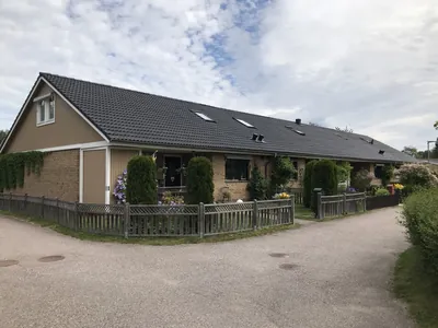 Efter: längan med kvistar och antracitfärgat tak sedd från gångvägen hos BRF. Påskliljan