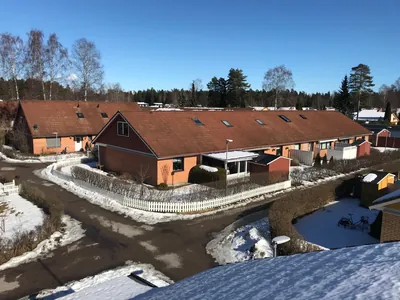 Före: radhuslänga med mörkbruna tak och vitt plank vid snötäckt gata hos BRF. Påskliljan