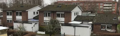 Före: tegelradhus med mörka, mossiga tak och vita förråd hos BRF. Rosen i Mariestad