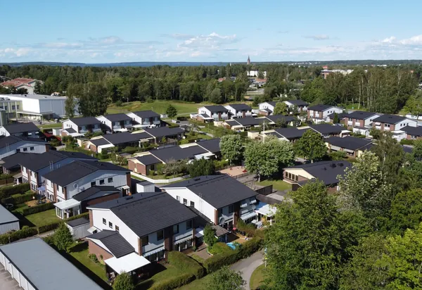 Drönarbild över radhus hos BRF. Rosen i Mariestad med färdigbehandlade antracitgrå tak bland träd