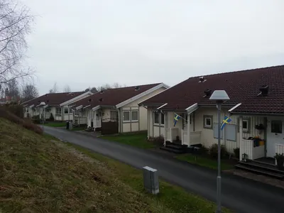 Före: grusväg med parhus och brunt, missfärgat tak i motljus hos BRF Rydet
