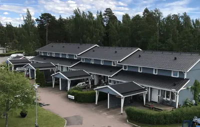 Efter: blågrå radhus med jämnt antracitgrått tak, fotat från taknivå hos BRF. Sommarvinden