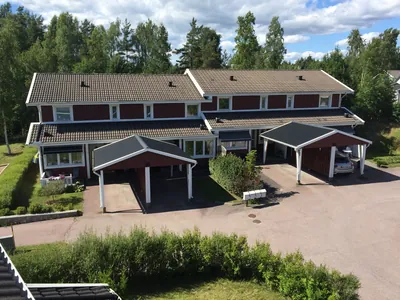 Före: röda radhus med ljusbruna, urblekta takpannor och carportar hos BRF. Sommarvinden