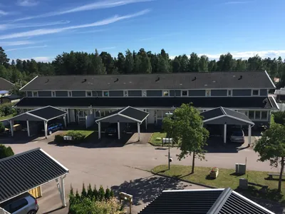 Före: blågrå radhuslänga med matt grått tak sedd från taket hos BRF. Sommarvinden