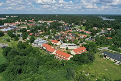 Efter: högt drönarperspektiv över BRF. Vårsången i Knivsta med behandlade tak mellan träd