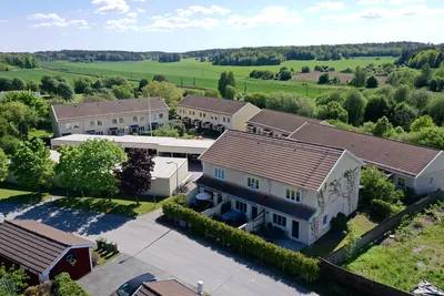 Före: radhus hos BRF. Vårsången med bleka, brungrå tak och carportlängor, fotat med drönare