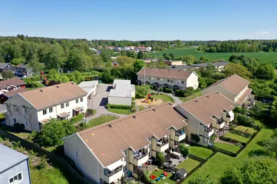 Före: radhuslängor med smutsiga, urblekta betongpannor hos BRF. Vårsången i Knivsta, drönarbild