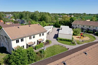 Före: radhusgavel med slitet, ljusbrunt tak och lekplats hos BRF. Vårsången i Knivsta