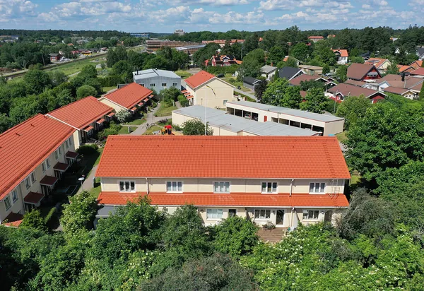 Drönarbild över radhuslängor hos BRF. Vårsången i Knivsta med nybehandlade kopparbruna tak omgivna av grönska