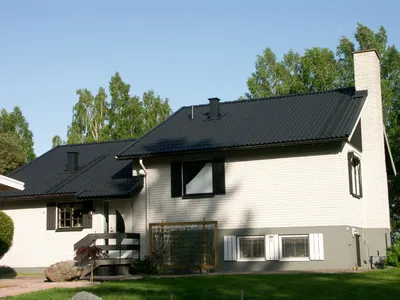 Efter: vitputsad villa med färdigbehandlat antracitgrått tak, fotad från trädgården