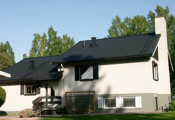 Vitputsad villa med grå sockel och nybehandlat antracitfärgat tak