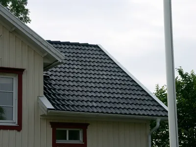 Efter: takfall med nybehandlade antracitpannor och vit vindskiva vid gulvit träfasad