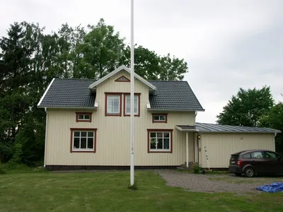 Efter: gulvita villan med färdigt antracittak sedd från gräsmattan, carport och bil till höger