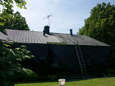 Under arbetet: tegelvillan inplastad i svart skyddsduk med stege mot taket