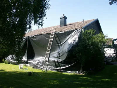 Under arbetet: villan inplastad i svart skyddsduk under tvättningen, stege mot taket