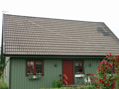 Under arbetet: den grönpanelade villan med nytvättat tak, rosor vid fasaden