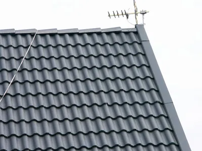 Efter: grönpanelad villa sedd från gräsmattan med färdigbehandlat tak i antracit