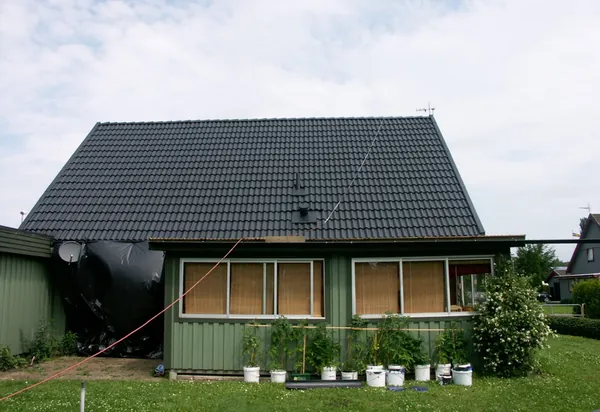Villa med grön träfasad och nybehandlat antracittak med takantenn, sedd från trädgården