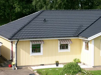 Efter: hörn av gul villa med färdigbehandlat antracittak och vita knutar