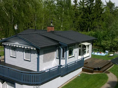 Efter: ljusgrå villa med blå knutar och färdigbehandlat antracittak, sedd från altansidan