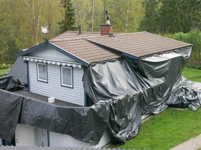 Före: huset med svart skyddsduk över fasaden inför takbehandlingen, brunbeige pannor ovanför