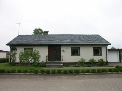 Efter: vit tegelvilla med färdigbehandlat antracittak och trimmad häck framför
