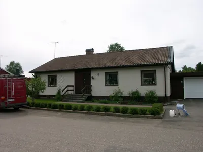 Före: vit tegelvilla med garage och brunt, urblekt tak sedd från gatan