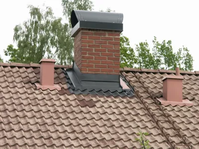 Före: närbild på rosabruna betongpannor intill tegelskorsten och ventilationshuvar