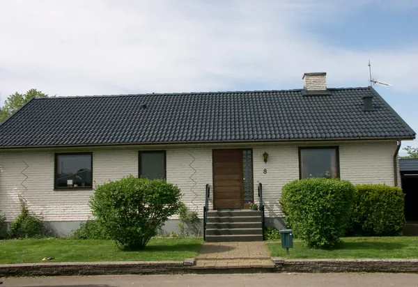 Vit tegelvilla med trädörr och svart smidesräcke, nybehandlat tak i antracit på grova Zanda-pannor